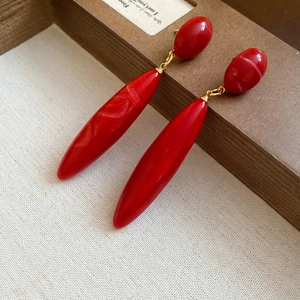 Macro shot of vibrant red acrylic teardrop earrings with elegant golden hardware