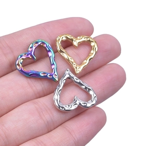 Textured heart pendants in rainbow, gold, and silver finishes on a hand palm