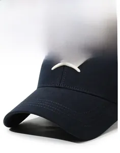 Détail montrant la broderie de couronne blanche sur une casquette en coton bleu marine