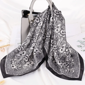 Dettaglio di un foulard in seta paisley bianco e nero drappeggiato su una borsa di lusso