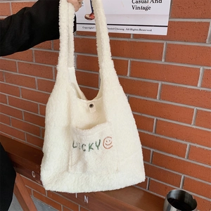 Detail der cremefarbenen Fleece-Tasche mit grüner Lucky-Stickerei und Smiley-Gesicht
