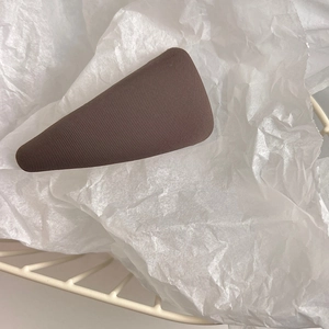 Detail view of dark brown triangular hair clip with ribbed texture in a wire basket