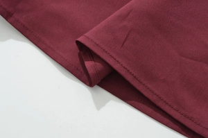 Close-up of double-needle stitching and burgundy cotton fabric texture on tank dress