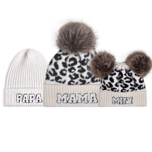 Detailed view of leopard print knit beanies with Papa Mama Mini embroidery and faux fur pom