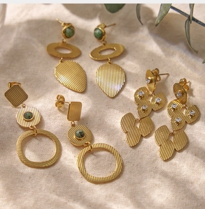 Détail de boucles d'oreilles vintage dorées 18K avec pierres naturelles vertes et zircons