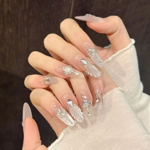Detailed view of almond-shaped press-on nails with 3D pearls, rhinestones and cat-eye effect