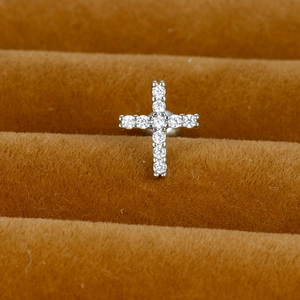 Macro shot of silver stainless steel cross earring with sparkling zircon stone pavé