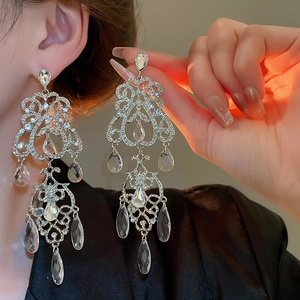 Détail de grandes boucles d'oreilles baroques argentées avec cristaux sur modèle