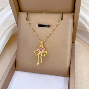 Detail of pink heart gemstone and golden bow pendant resting on a luxury jewelry box