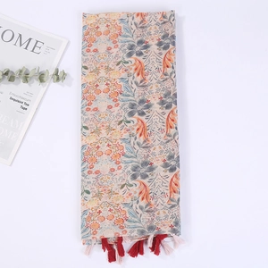 Detail of floral linen beach shawl with colorful tassels and soft bohemian print pattern