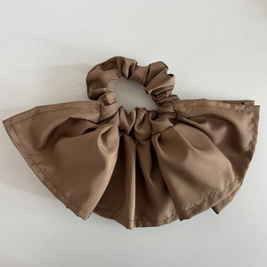 Detailed close-up showing the brown pleated satin fabric texture of this scrunchie