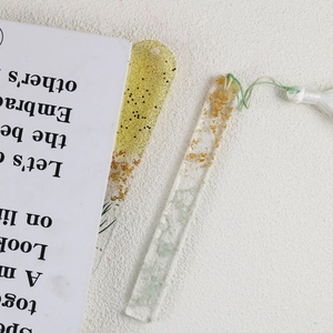 Macro shot of handmade resin bookmarks with gold flakes, green tassels, and clear texture