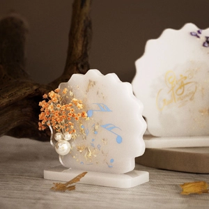 Macro detail of wave-edged resin frame with dried flowers, pearls and gold foil elements