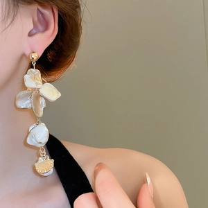 Detail of long irregular shell fringe earrings in gold finish worn by a model