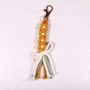 Handwoven yellow daisy keychain featuring cotton tassels and a durable metal clasp detail