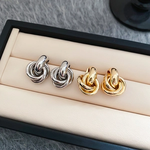 Nahaufnahme von verdrehten Knotenohrringen in Gold und Silber in einer Schmuckschatulle