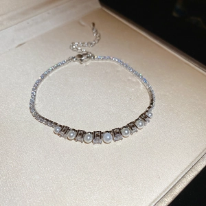 Close-up of pearl and zircon bracelet with heart pendant charm and adjustable link chain