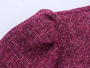 Macro shot showing the burgundy tweed fabric texture and woven fiber details of the suit