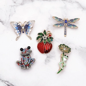 Assorted insect brooches with rhinestones and enamel on white marble background