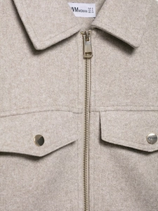 Close-up of oatmeal tweed jacket featuring light gold metal zipper and pocket hardware