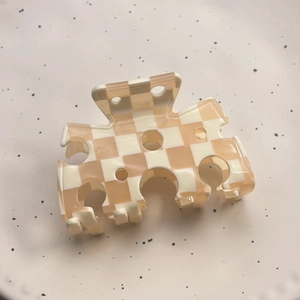 Detail of cream checkerboard acetate hair claw clip with round cut-outs on ceramic plate
