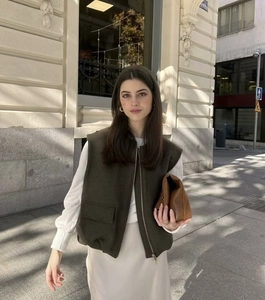 Detailed view of women's sleeveless military green vest with zipper and large pockets