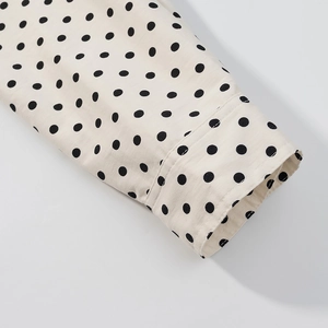 Detail macro-opname van polkadotpatroon en stiksels op de manchet van een beige jas