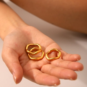 Set of three gold plated stainless steel wavy geometric rings displayed on a palm