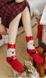 Close-up of fluffy Santa Claus Christmas socks in red coral fleece with festive 3D details