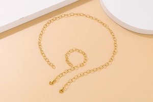 Flat lay of a gold link chain necklace and bracelet set on geometric panels