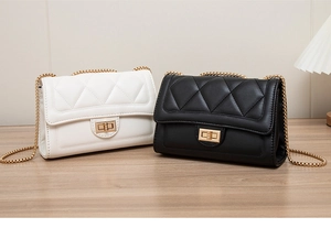 Detail of white and black quilted chain bags with gold clasps on a wooden table