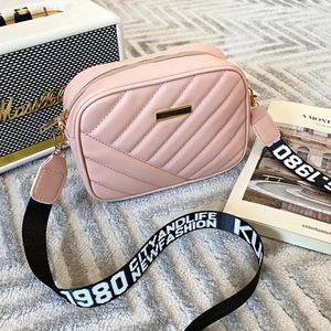 Detail of pink quilted crossbody camera bag with adjustable wide lettered shoulder strap