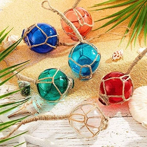 Decorative glass fishing floats with jute rope netting on a sandy summer beach