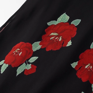 Macro detail of red floral print on lightweight black chiffon fabric with soft leaves