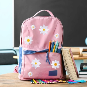 Pink daisy embroidered school backpack with blue zipper detail in a classroom setting