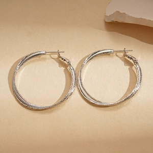 Macro shot of large silver hoop earrings featuring a spiral twisted double cross texture
