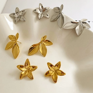 Elegant gold and silver leaf and flower-shaped earrings displayed on a white tray