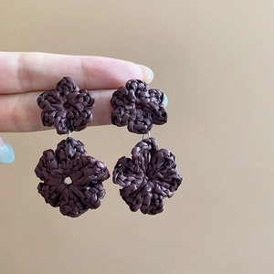 Close-up of handmade dark brown woven flower earrings with double layer floral design