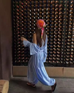 Light blue loose-fit jumpsuit paired with a colorful floral silk headscarf in a wine cellar