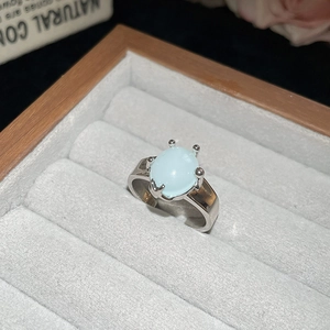 Macro view of light blue oval stone ring with silver four-prong setting in a grey gift box