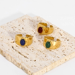 Gold plated stainless steel ring set with oval natural stones on travertine stone