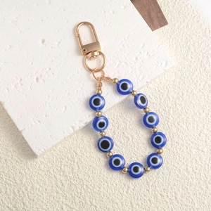 Detail of beaded evil eye keychain with blue resin beads and golden metal ring clasp