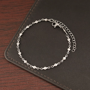 Detail of silver chain bracelet with diamond and round links on leather background