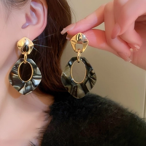 Close-up of leopard star gold hoop earrings with marble texture on model's hand