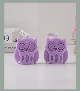 Detail of two lavender owl-shaped scented candles on a white surface for home decor