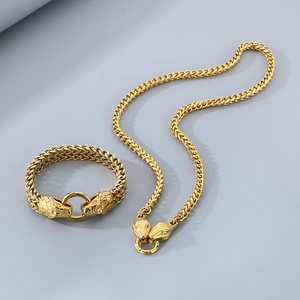 Detail view of golden stainless steel snake head bracelet and necklace set on gray background