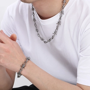 Detailed view of thorn-shaped titanium steel necklace and bracelet set on male model