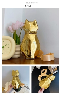 Detail of a gold cat-shaped patent leather crossbody bag with adjustable wide strap