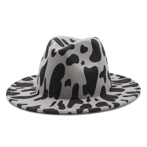 Detail of grey fedora hat with black cow print pattern and flat brim on white background