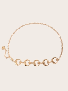 Détail de la chaîne de taille en métal doré avec des pendentifs lune et étoiles